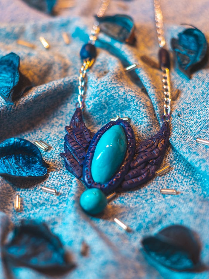 home-img Close-up of a handcrafted blue stone necklace on textured fabric with clay and beads.